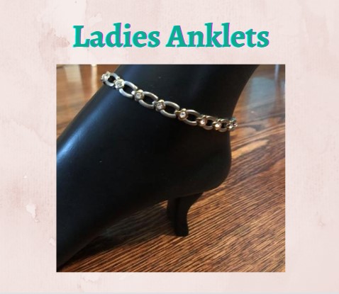 This is a picture of a silver crystalized anklet on a black statue figurine having a caption of 'Ladies Anklets